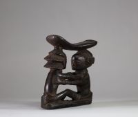 Ancien appui-nuque Luba « Shankadi », Congo RDC. Très bel exemplaire représentant deux figures humaines assises face à face, les bras posés sur les épaules de l’autre, dans une posture d’étreinte rituelle. Chacune soutient une tablette repose-nuque incurvée. L’une des figures présente une coiffure en croix (tulume) et l’autre une coiffure en cascade ( dans la tradition du maître de Kalundwe) . Les
