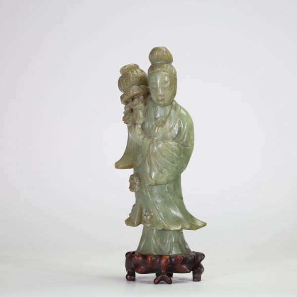 Statuette en jade céladon représentant une élégante, Chine, dynastie Qing, XIXe siècle Sculptée dans une pierre jade céladon nuancée, la figure incarne une jeune femme debout tenant un vase fleuri à l