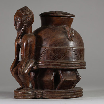Oracle à souris ( bo num) Baoulé,  côte d’Ivoire. Bois dense, relativement ancien, à patine brune, représentant une figure masculine  assise, soutenant un récipient divinatoire circulaire finement décoré. Un trou circulaire obturé sous la base atteste de l’usage rituel de cette pièce, destinée aux pratiques divinatoires du devin (komien). Le style correspond à la statuaire Baoulé classique du cent