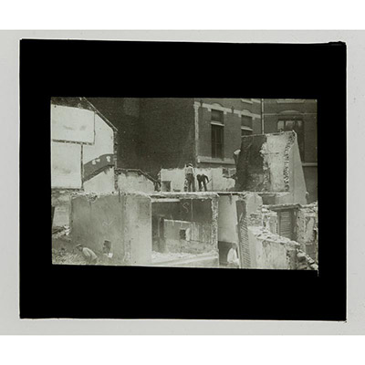 Léon Herlant (1873-1968) — 2 photos positives sur plaques de verre, 8,5 x 10 cm.  Cet ensemble de deux plaques photo positives noir et blanc capture la scène d’un chantier urbain à Bruxelles au 19e siècle, probablement dans la rue du Marais, une rue emblématique de la ville. La scène prend place dans un quartier où l’architecture néo-classique bruxelloise est omniprésente. Les bâtiments à l’esthét
