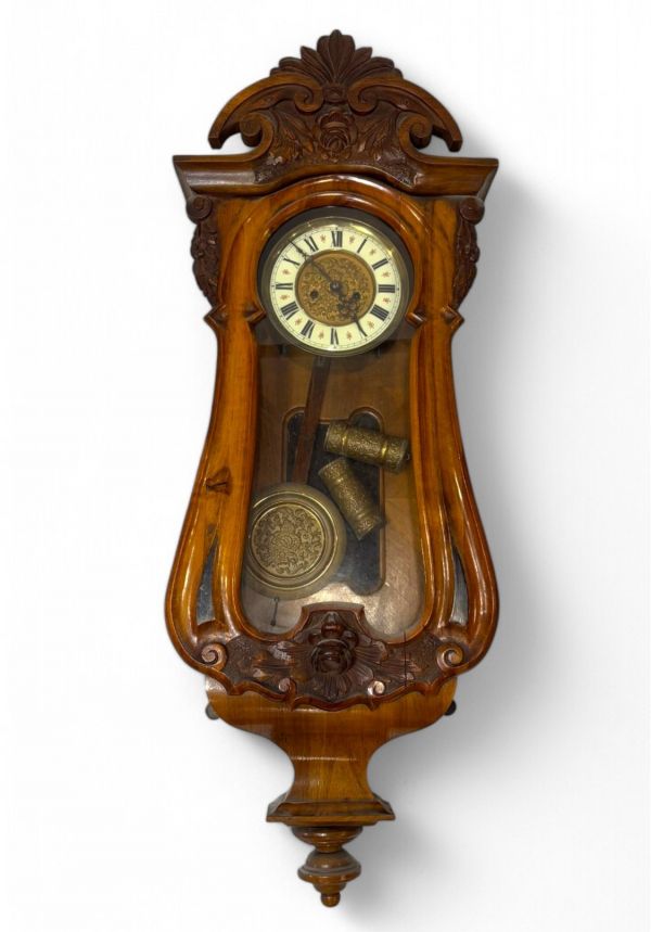 Pendule d'applique en noyer sculpté et placage, caisse moulurée et vitrée, cadran à chiffres romains, fin XIXème.