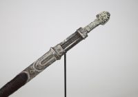Poignard persan à décor d'argent, début XIXᵉ siècle Poignard oriental monté en argent repoussé et ciselé, présentant une garde et un fourreau richement ornés de motifs floraux et de cartouches géométriques, caractéristiques de l’art décoratif perse. Le pommeau bombé et la garde sont rehaussés de filets floraux, certains émaillés de bleu.  La lame à double tranchant, probablement forgée en acier, e