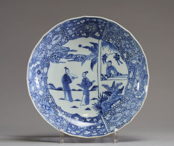 Chine - Assiette festonnée en porcelaine blanc bleu à décor de personnages, motif floral sous la pièce.