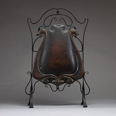 Par-feu Art Nouveau, monture en fer forgé patiné noir aux motifs de volutes, grand décor central en cuivre repoussé fixé par fils de fer.