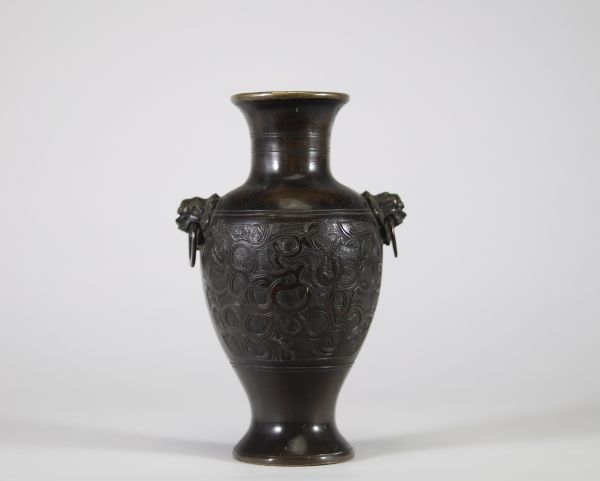 Vase en bronze à décor archaïsant et anses en têtes de lion, Chine Élégant vase en bronze de forme balustre, reposant sur un pied évasé et doté d’un col évasé à bord légèrement ourlé. Le corps est entièrement orné en léger relief d’un décor sinueux de rinceaux et volutes évoquant les motifs archaïques de la période des Royaumes Combattants ou des bronzes rituels Shang-Zho