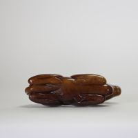 Chine, XIXe siècle. Chameau couché en jade néphrite brun, sculpté avec sobriété dans une posture stylisée, symbolisant la route de la soie et la persévérance.