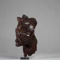 Ancien masque tribal avec coiffe « Mwana pwo » Chokwe/ Tshokwe, RD Congo, Angola. Bois, raphia. Le visage est de forme légèrement allongée, avec un front large et bombé qui s'effile vers un menton délicat. Les proportions sont harmonieuses, créant une impression de calme et de sérénité. Nez fin et droit. Nombreuses scarifications dont « cingelyengelye » sur le front, l’emblème royal. Très belle pa