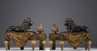 Paire de chenets en bronze patiné et doré représentant des lions couchés devant une flamme, XIXème.