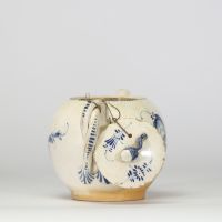 Boch Luxembourg, fin XVIIIe – début XIXe siècle Petite théière en porcelaine fine à décor bleu Théière de forme globulaire à décor peint en bleu sous couverte de réserves rocaille, feuillages et fleurettes stylisées.