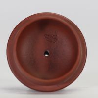Théière globulaire en terre cuite pourpre, dite zisha, typique de la production de Yixing. Elle présente un panse arrondi, un court bec conique et une anse semi-circulaire.