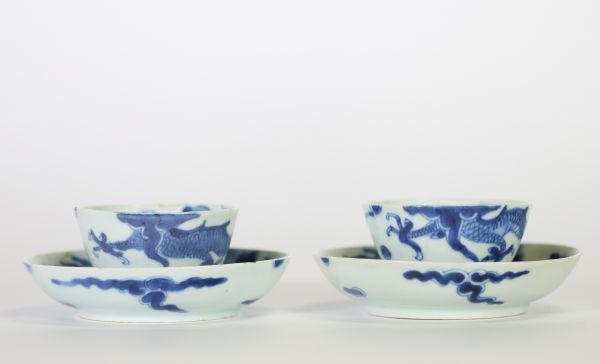 Chine, dynastie Qing – Ensemble de quatre bols et soucoupes en porcelaine bleu et blanc à décor de dragons parmi les nuées