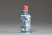 Chine - Tabatière en porcelaine blanc bleu et rouge fer à décor de dignitaires, bouchon en corail.