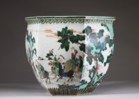 Rare et spectaculaire vase en porcelaine de forme hexagonale, décoré en émaux de la famille verte. Chaque pan du corps présente une scène animée mettant en scène des dignitaires, serviteurs et immortels dans un paysage arboré ponctué de pins, rochers et nuées stylisées. Les personnages, finement détaillés, sont représentés à cheval, à pied ou en conversation, dans un esprit narratif typique de la