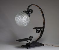 André HUNEBELLE (1896-1985) dans le goût de - Lampe pied fumer en fer forgé martelé et globe en verre moulé pressé à décor de visages de femmes, vers 1920-30.