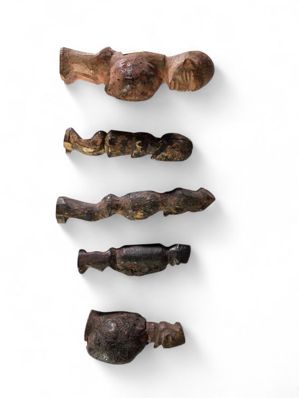 Ensemble de cinq figurines rituelles miniatures Yaka, RD Congo, bois, raphia. H : de 7 à 11 cm. Rare ensemble de petites figurines anthropomorphes utilisées dans le contexte rituel des Yaka (Kwango-Kwilu), au sud-ouest de la RDC. Ces sculptures miniatures, marquées par une forte stylisation et des traces rituelles (pigments, craquelures, dépôt), étaient utilisées comme fétiches de protection ou de