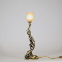 Raoul François Louche (actif au début du XXe siècle) Lampe Art Nouveau en bronze doré et patiné, verrerie signée Schneider  Rare et délicate lampe de table en bronze à patine nuancée représentant une femme nue, élancée et drapée dans un mouvement tourbillonnant, typique du style naturaliste et sensuel de l’Art Nouveau. Le personnage féminin s’élève avec grâce pour former le corps du luminaire, ses