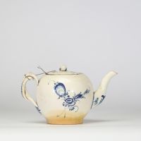 Boch Luxembourg, fin XVIIIe – début XIXe siècle Petite théière en porcelaine fine à décor bleu Théière de forme globulaire à décor peint en bleu sous couverte de réserves rocaille, feuillages et fleurettes stylisées.