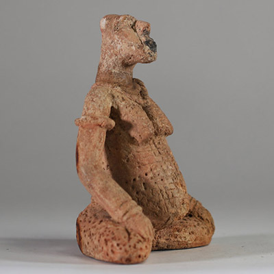 Rare statuette en terre cuite Djenné, Mali. XIème- XIVème siècle apr. J.-C. ( restauré). La figure est représentée assise, les jambes écartées et repliées symétriquement, dans une posture évoquant l’introspection ou le recueillement rituel. Le torse est orné de scarifications en damier et les seins sont traités en relief. Le visage, à la bouche proéminente, conserve des traces de pigments rouges e