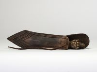Rare phurba tibétain avec son fourreau, triple lame triangulaire et décoré à la poignée d’une tête de divinité courroucée finement ciselée son fourreau d’origine en cuir gravé, de forme effilée, avec son cordon de suspension, élément rare pour ce type d’objet. probablement XVIIIe siècle