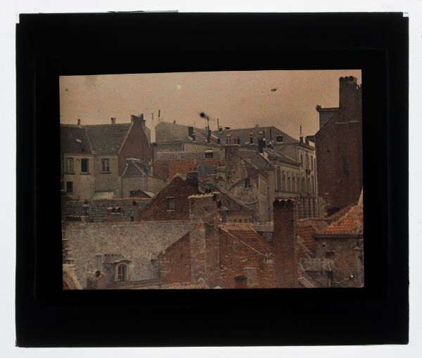 Léon Herlant (1873-1968) — 1 autochrome sur plaque Lumière, 8,5 x 10 cm.  Autochrome Vue rapprochée des Toits de Bruxelles vers 1910 — Un témoignage du Vieux Bruxelles avant la Bruxellisation  Cette vue rapprochée des toits de Bruxelles, prise vers 1910, capture la beauté intemporelle du Vieux Bruxelles, un moment de l’histoire architecturale de la ville avant sa transformation radicale par la Bru