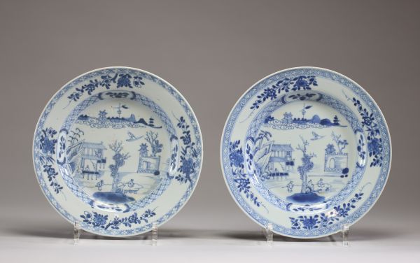 Chine - Paire d'assiettes en porcelaine blanc bleu à décors de personnages et de temple, époque Kangxi.
