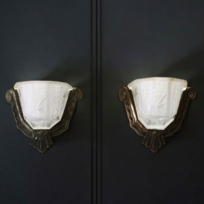 A pair of Art Deco sconces in pressed moulded glass with geometric motifs and silvered bronze mountings, circa 1930.