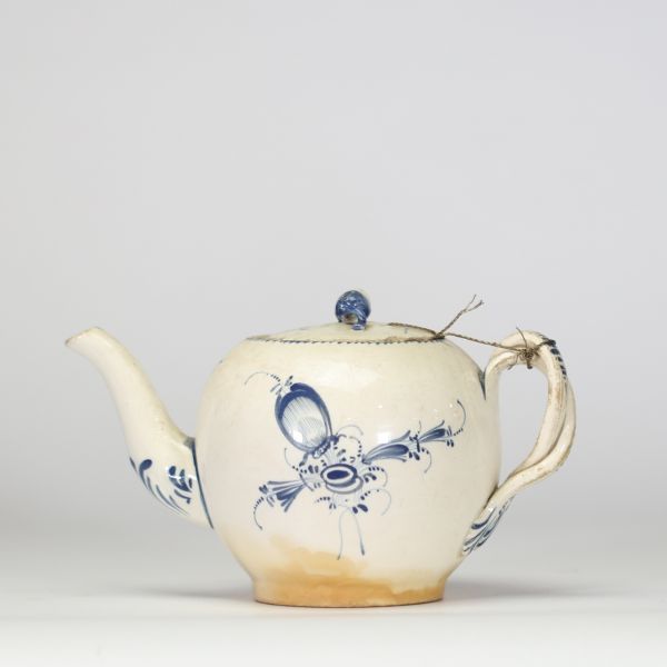 Boch Luxembourg, fin XVIIIe – début XIXe siècle Petite théière en porcelaine fine à décor bleu Théière de forme globulaire à décor peint en bleu sous couverte de réserves rocaille, feuillages et fleurettes stylisées.