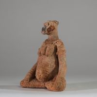 Rare statuette en terre cuite Djenné, Mali. XIème- XIVème siècle apr. J.-C. ( restauré). La figure est représentée assise, les jambes écartées et repliées symétriquement, dans une posture évoquant l’introspection ou le recueillement rituel. Le torse est orné de scarifications en damier et les seins sont traités en relief. Le visage, à la bouche proéminente, conserve des traces de pigments rouges e