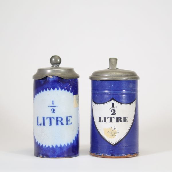 Lot de deux chopes en faïence émaillée de Bruxelles, à décor bleu cobalt et inscriptions « ½ LITRE » en réserve. Chaque pièce est coiffée d’un couvercle en étain fin XIXe – début XXe