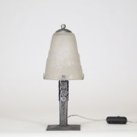 Muller Frères, Lunéville, vers 1930 Ensemble de deux lampes Art Déco en verre moulé-pressé et monture en métal ouvragé à finition nickelée mate.  Chacune des lampes repose sur une base rectangulaire en métal travaillé au repoussé, présentant une surface texturée de motifs géométriques martelés typiques de la période Art Déco. Le fût vertical, orné de pastilles et de stries régulières, soutient une