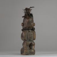 Ancienne figure rituelle en pierre  Bakongo, RD Congo. Travail de sculpture très fin. Le personnage a les mains posées sur le bilogo, protégé par un morceau de miroir. Le sommet du crâne est creusé et contient des plumes anciennes, renforçant sa dimension rituelle. Les jambes, le dos et les joues présentent des motifs gravés en croisillons, typiques de l'art Yombe. Un cordon textile est encore vis
