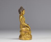 Sculpture d'un bouddha assit sur un socle en bronze doré