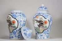 Asie, XXᵉ siècle – Paire de potiches couvertes en porcelaine à décor de lions en cartouches sur fond floral bleu et blanc
