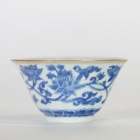 Chine, bol en porcelaine blanc-bleu à décor de fleurs de lotus épanouies et en bouton surmontant une frise de vagues, l'intérieur orné d'une fleur stylisée et la base portant une marque apocryphe à si