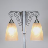 J. Vandôme & Muller Frères Lunéville, vers 1930 Lampe Art Déco à deux lumières en métal martelé nickelé et verrerie signée.  Structure en potence à deux bras terminés par d’élégantes volutes martelées, surmontant un fût vertical en métal à décor rayonnant. La base rectangulaire est signée J. Vandôme, artisan ou maison d’édition réputée pour ses œuvres de ferronnerie décorative dans les années 1930