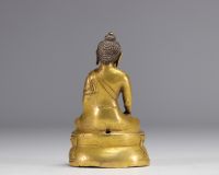 Sculpture d'un bouddha assit sur un socle en bronze doré