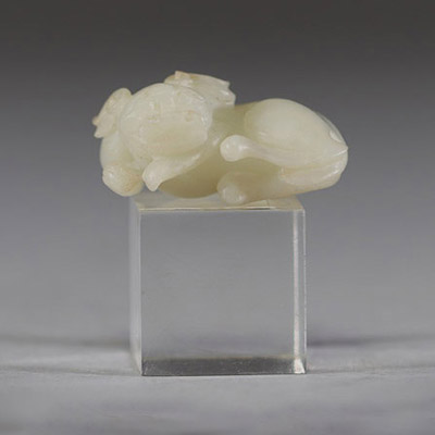 Chine - Sculpture en jade blanc représentant un chien chinois, fin de la dynastie Qing Sculpture délicatement taillée dans un jade blanc de belle qualité, figurant un chien chinois couché, le corps ramassé et la tête tournée vers l’avant. Le jade présente une teinte douce et homogène, typique des œuvres réalisées à la fin de la dynastie Qing. Le sujet animalier, fréquent dans l’art chinois, symbol