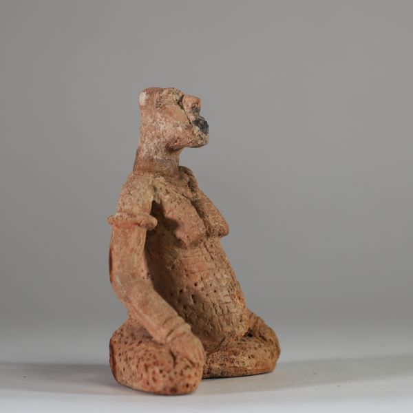 Rare statuette en terre cuite Djenné, Mali. XIème- XIVème siècle apr. J.-C. ( restauré). La figure est représentée assise, les jambes écartées et repliées symétriquement, dans une posture évoquant l’introspection ou le recueillement rituel. Le torse est orné de scarifications en damier et les seins sont traités en relief. Le visage, à la bouche proéminente, conserve des traces de pigments rouges e