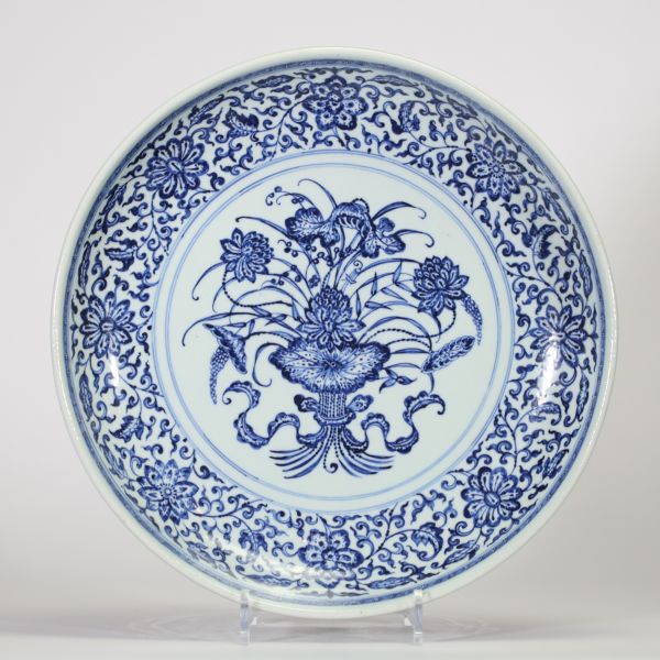 Grand plat en porcelaine de Chine bleu et blanc à décor d’un panier fleuri dans un médaillon central, entouré d’une large frise florale, probablement dynastie Qing, XVIIIe siècle.