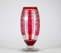 Vase Art Déco en cristal doublé rouge à décor géométrique et floral, attribué à Baccarat Vase de forme balustre en cristal doublé rouge rubis, à décor géométrique structuré par des pans coupés verticaux alternant motifs lisses et réserves gravées à l’acide d’un décor floral stylisé. Le corps repose sur un piédouche circulaire taillé en étoile.