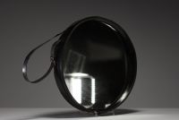 Jacques ADNET (1900-1984) Wall-mounted mirror with circular metal frame entirely sheathed in black leather, fastening strap ending in a brass buckle, circa 1950.