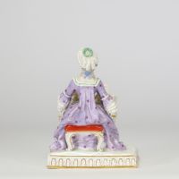 Figurine en porcelaine polychrome de la manufacture de Meissen « Jeune femme devant un petit piano ou clavecin. La base à décor moulé de lambrequins dorés repose sur un socle rectangulaire. Marque aux