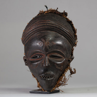Ancien masque tribal avec coiffe « Mwana pwo » Chokwe/ Tshokwe, RD Congo, Angola. Bois. Très bel exemplaire bien conforme avec les yeux mi clos en « amande », le nez fin et allongé, la bouche entre-ouverte avec des dents « limées ». La coiffe ( samunganda) en raphia est élaborée et symbolise la coiffure des femmes de haut rang.  La patine est profondeet typique des masques ayant été frottés avec d